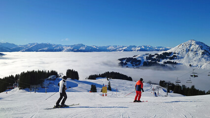 Ski Resort and beautiful sight of alps with lower clouds underneath a clear blue and sunny sky. Lots of fog and mist in the valley of Westendorf, Austria (Tirol).