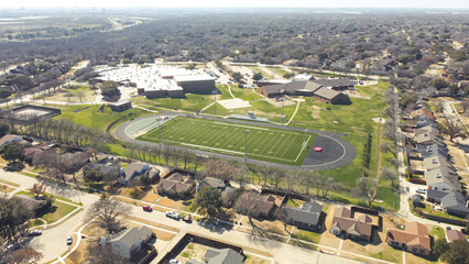 Middle school football stadium with artificial turf, yard markings, track and field situated in...