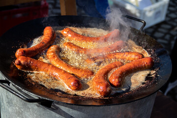 Street Food cooking on big frying pan, tasty home made sausages on large commercial griddle hotplate, food festival at country side of Serbia