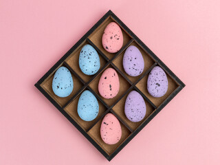 Colorful Easter eggs in a box on the pink background