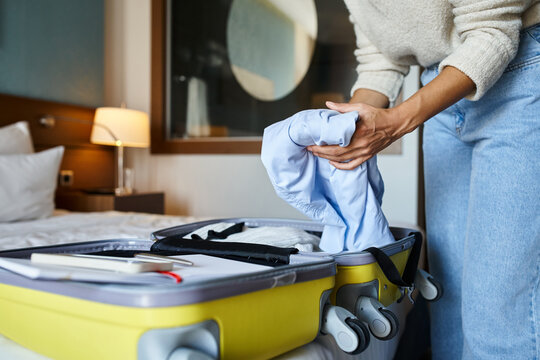 Cropped View Of African American Woman Packing Her Blue Shirt In Suitcase, Solo Traveler Concept