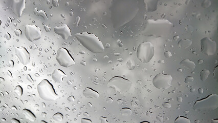 Raindrops texture on window with dark clouds in the background.