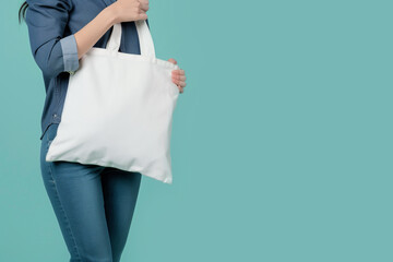 Girl carrying blank white tote bag canvas fabric, mockup. Copy space. Say no to plastic bags concept