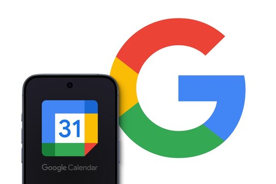 Google Calendar Logo shown on a modern smartphone, big Google logo in the background, time-management and scheduling calendar service developed by Google