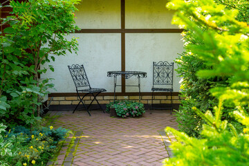Patio with openwork wrought-iron furniture in the summer garden