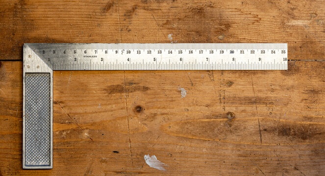 Close up of stainless L square on wooden work bench