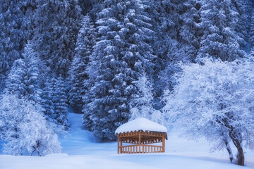 Cozy wooden gazebo in a snowy forest in the winter mountains after a snowfall