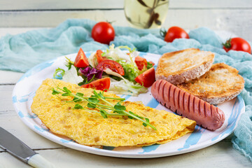 Fried omelette with sausage and salad. Delicious breakfast with eggs and toast