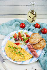 Fried omelette with sausage and salad. Delicious breakfast with eggs and toast