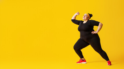 Fototapeta na wymiar A lively woman dressed in a striking black ensemble and vibrant yellow headband effortlessly moves through a dance routine, her active pants hugging her toned physique as she gracefully flexes her kn