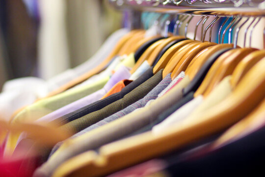 A line of shirts hanging on coat hangers in a second hand store