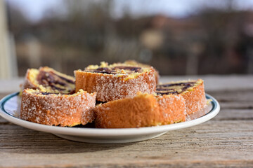 Home made swiss roll cake  with organic eggs and  peach jam covered with sugar on wooden background.  Healty natural dessert