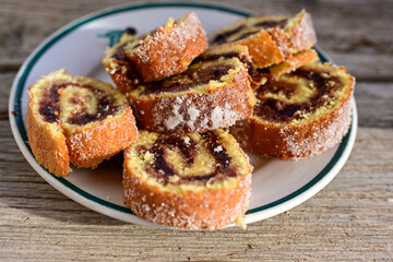 Home made swiss roll cake  with organic eggs and  peach jam covered with sugar on wooden background.  Healty natural dessert