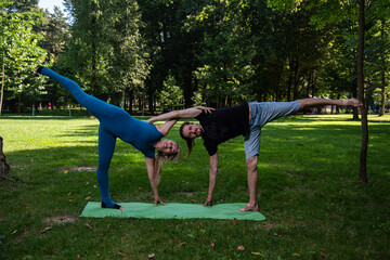 Boy and girl doing acro yoga outdoors in summer in public park