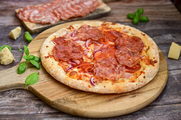 Home made italian  pepperoni   pizza with  tomatoes, mozzarella and parmesan cheese and fresh basil  on wooden background