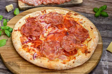 Home made italian  pepperoni   pizza with  tomatoes, mozzarella and parmesan cheese and fresh basil  on wooden background