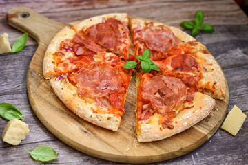 Home made italian  pepperoni   pizza with  tomatoes, mozzarella and parmesan cheese and fresh basil  on wooden background