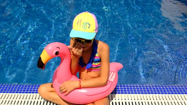 a child swims in a circle of flamingos in the pool. Selective focus.