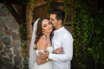 Young white groom kisses the bride on the cheek