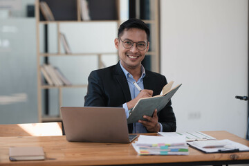 Fototapeta premium Joyful and Intelligent Entrepreneur Crafting Ideas with Laptop in Office Workspace.
