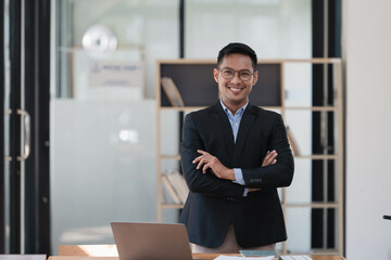 Portrait of young Asain businessman in suit with arms crossed in the office.