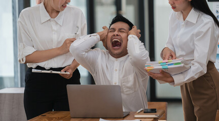 Obraz premium Frustrated Asian employee feels stressed suffers from hostile coworkers.