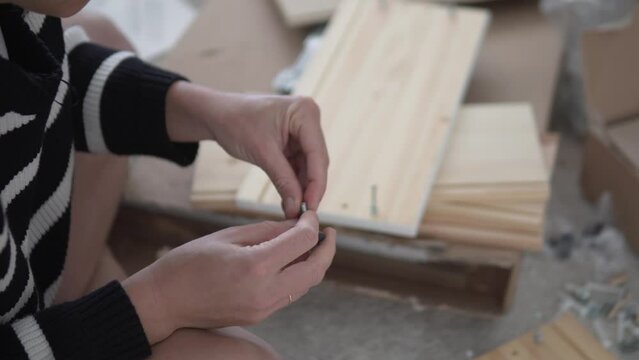 A woman assembles a wooden cabinet at home according to the instructions