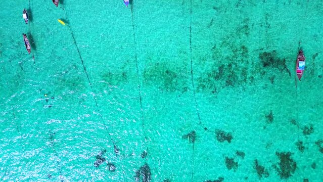 longtail boats in turquoise ocean on beach. Smooth aerial top view flight drone