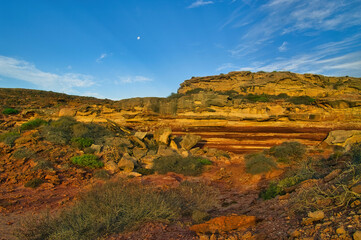 Deep reddish-brown an ochre colours during sunset at the rugged rocky landscape at the coast of...