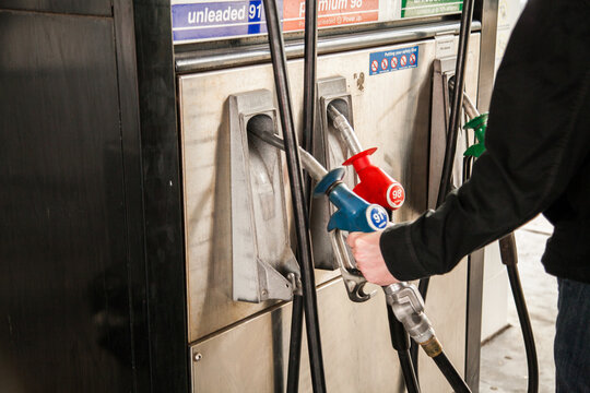 Man lifting petrol pump nozzle to fill up car with fuel