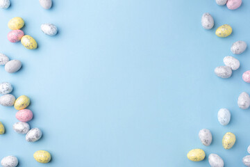 Festive Easter background. Multicoloured Easter eggs on a blue table. Card with a place for text. Top view.