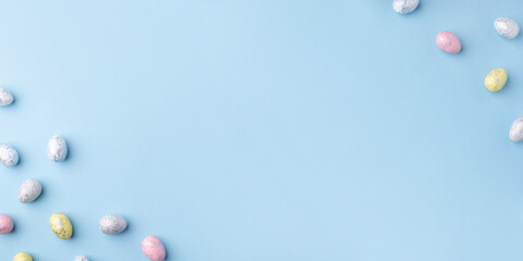 Festive Easter background. Multicoloured Easter eggs on a blue table. Banner with a place for text. Top view.