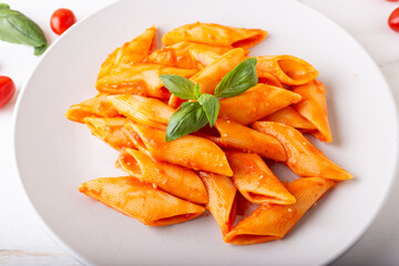 Pasta with fresh tomatoes sauce and basil. Penne with tomatoes served on a white background. Italian typical dish.