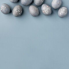 Festive Easter background. Gray-blue Easter eggs with stars on a blue table. Banner with a place for text. Top view.