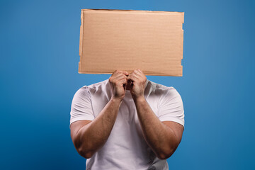 Man holding a cardboard sign in front of his face