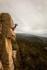 Person climbing in high mountains with yellow jacket rope and helmet in nature, confidence and risk, safety