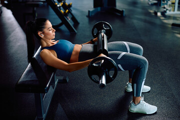 Young athletic woman having weight training in gym.