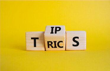Tips and Tricks symbol. Wooden cubes with words Tricks and Tips. Beautiful yellow background....