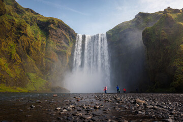 Group of tourists looking at the impressive Skogafoss waterfall in southern Iceland. Travel...
