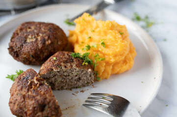German meatballs with potato puree and sweet potatoes on a plate. Traditional cuisine