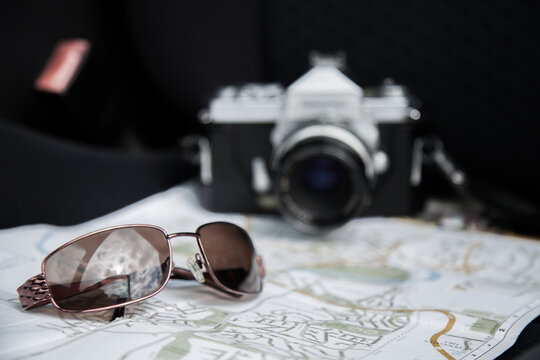 Sunnies and camera on map in car passenger seat