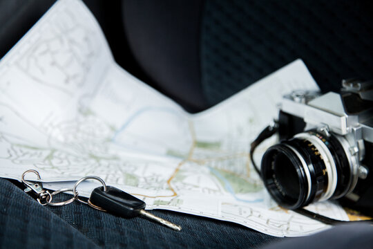 Car keys and vintage film camera with map on car seat