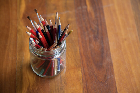 Graphite art pencils in jar on wood with copy space
