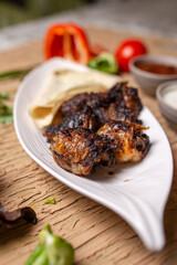 liver kebab with pita bread on a white plate with vegetables and herbs