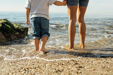 mother and son holding hands on the seashore. psychology of communication with children. family sea walk