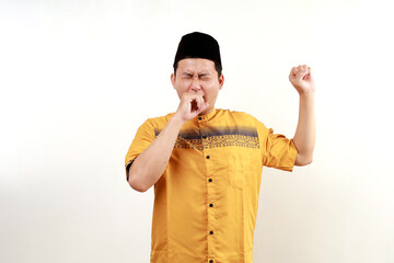 Young asian muslim man standing while yawning. Sleepy in ramadan month concept