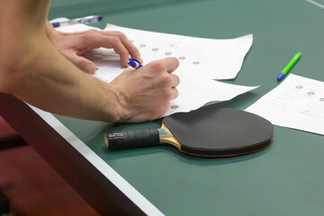 Person's Hands filling out ping pong tournament table - close up