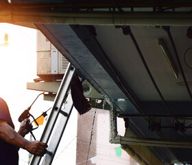 The technician is spraying water to clean the air conditioner.