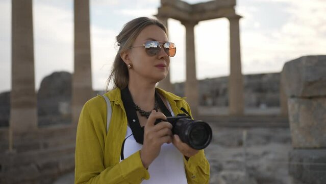 Woman tourist with a camera in the Acropolis on an excursion.