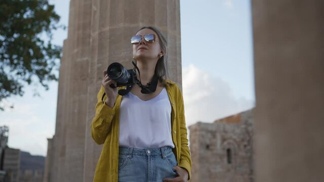 Woman tourist with a camera in the Acropolis on an excursion.